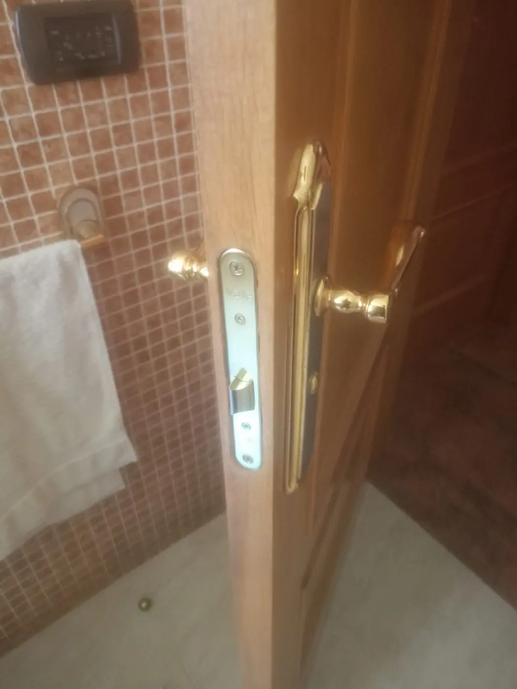 Placa y cerradura de una puerta de baño desmontadas sobre la propia hoja para liberar la condena