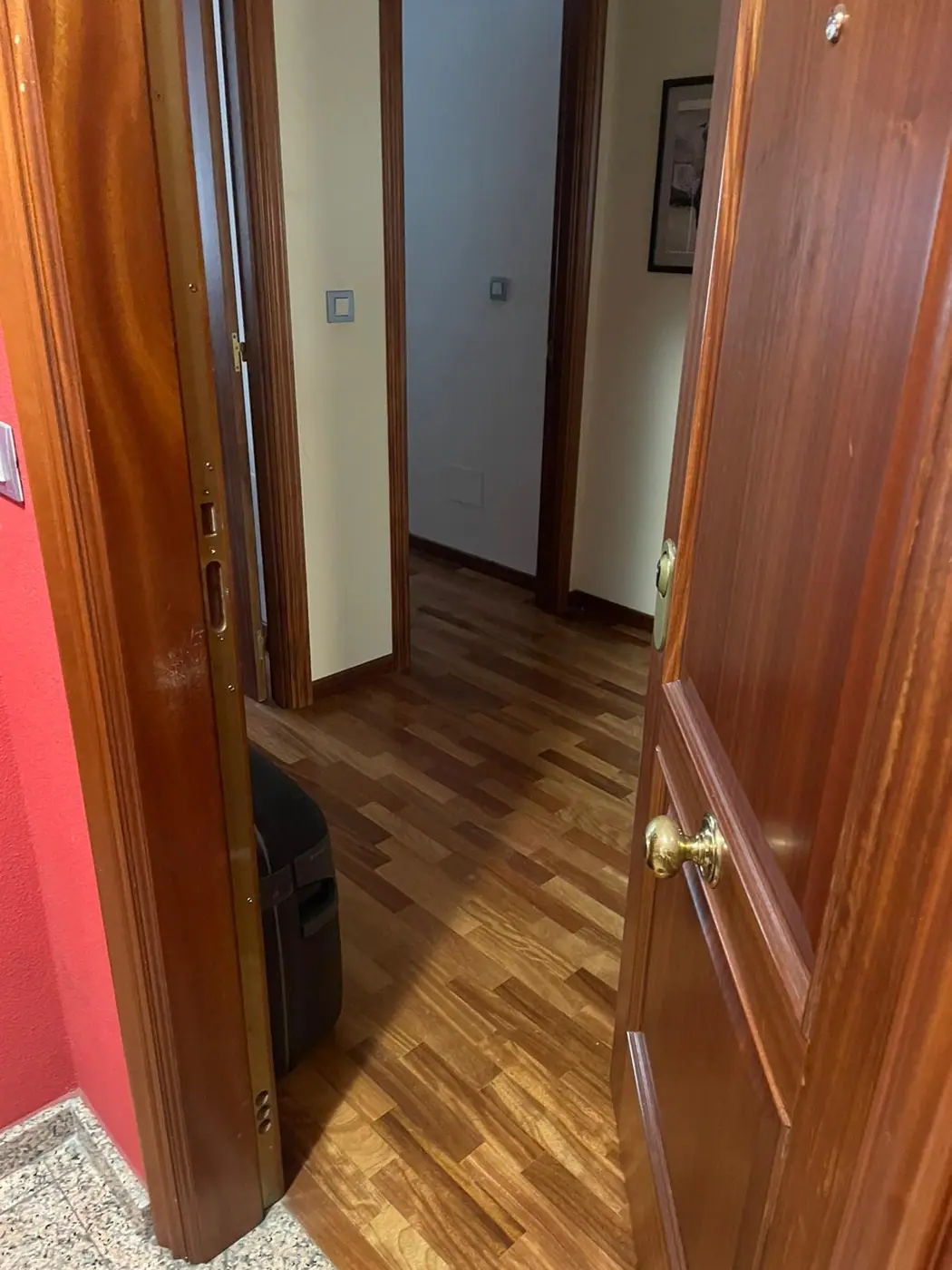 Puerta de paso de madera abierta con la manilla y el bocallave dorados a la vista
