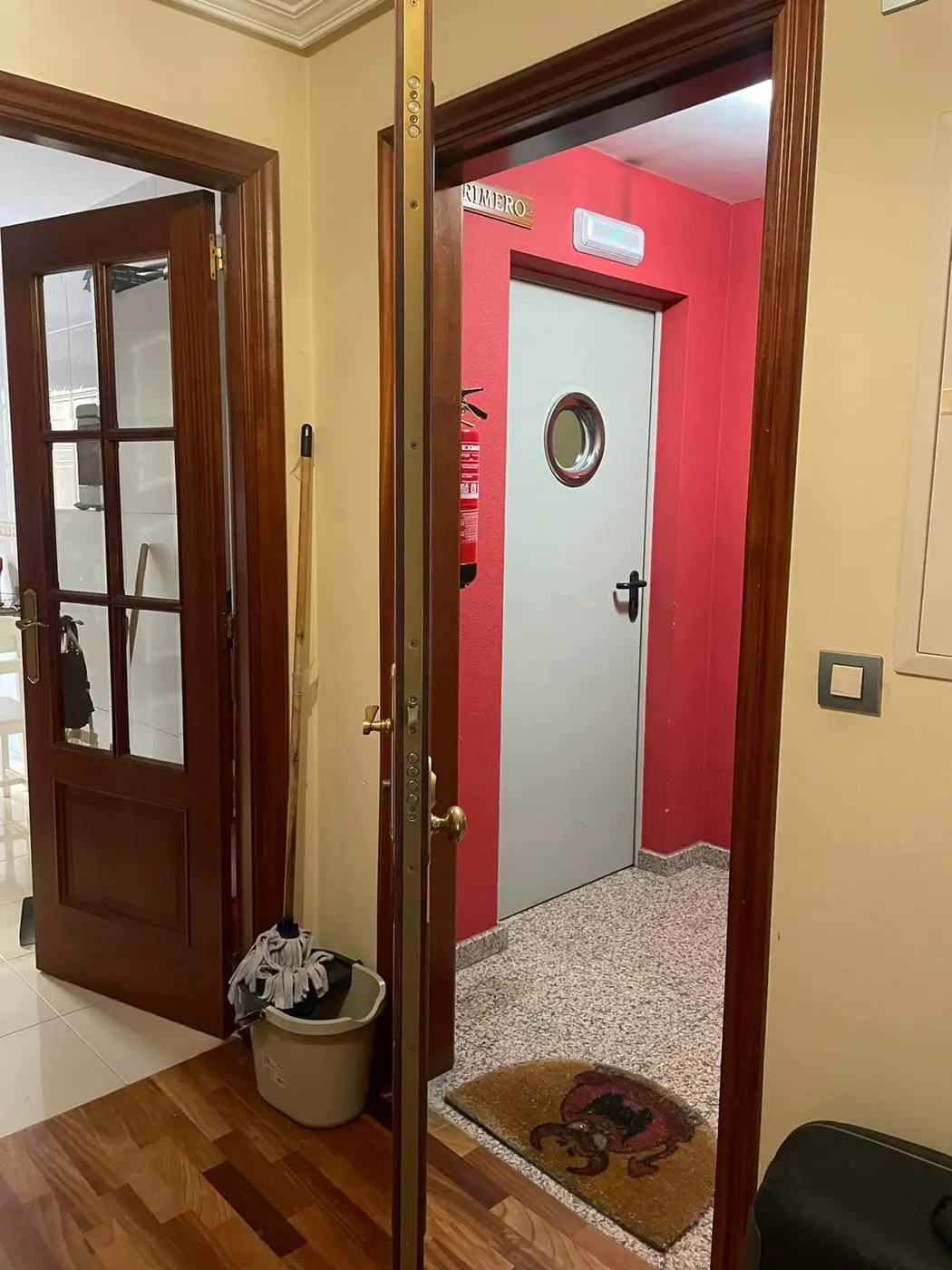 Recibidor de una vivienda de A Coruña con las puertas de paso y la puerta de entrada al fondo