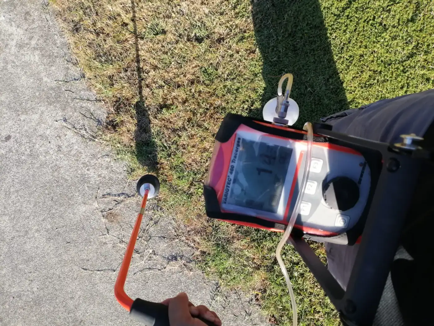 Sonda de campana apoyada sobre el pavimento y detector de gas trazador tomando lectura durante la localización de una fuga