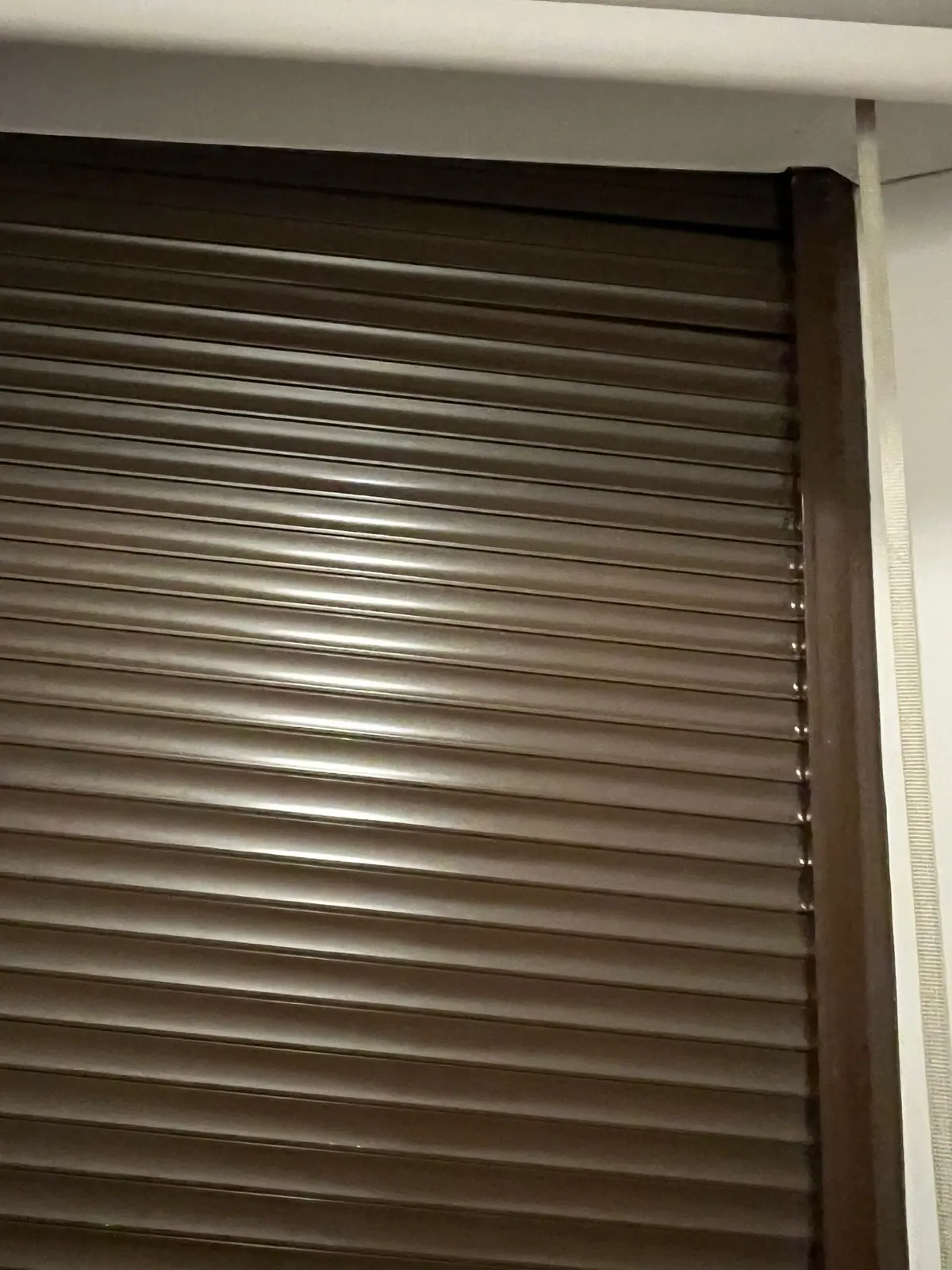 Persiana de aluminio marrón completamente bajada, vista desde el interior de la vivienda