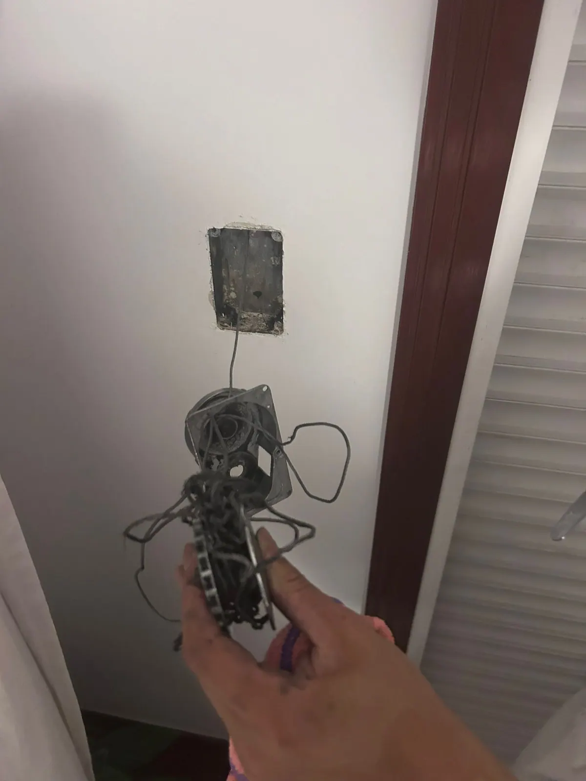 Recogedor de persiana desmontado con la cinta partida y enredada, junto al hueco vacío que deja en la pared