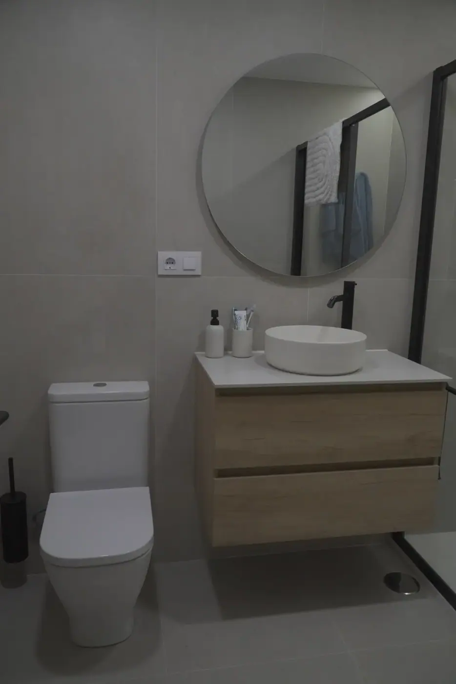 Baño con mueble suspendido de madera, lavabo sobre encimera y grifería negra