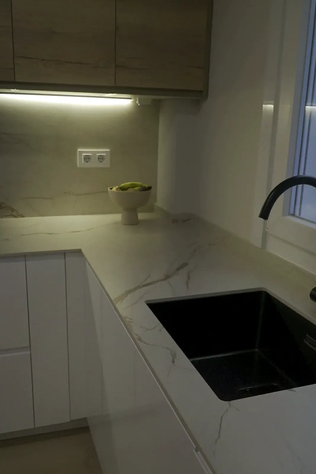 Cocina reformada en A Coruña con encimera de porcelánico Calacatta, muebles de roble y fregadero negro