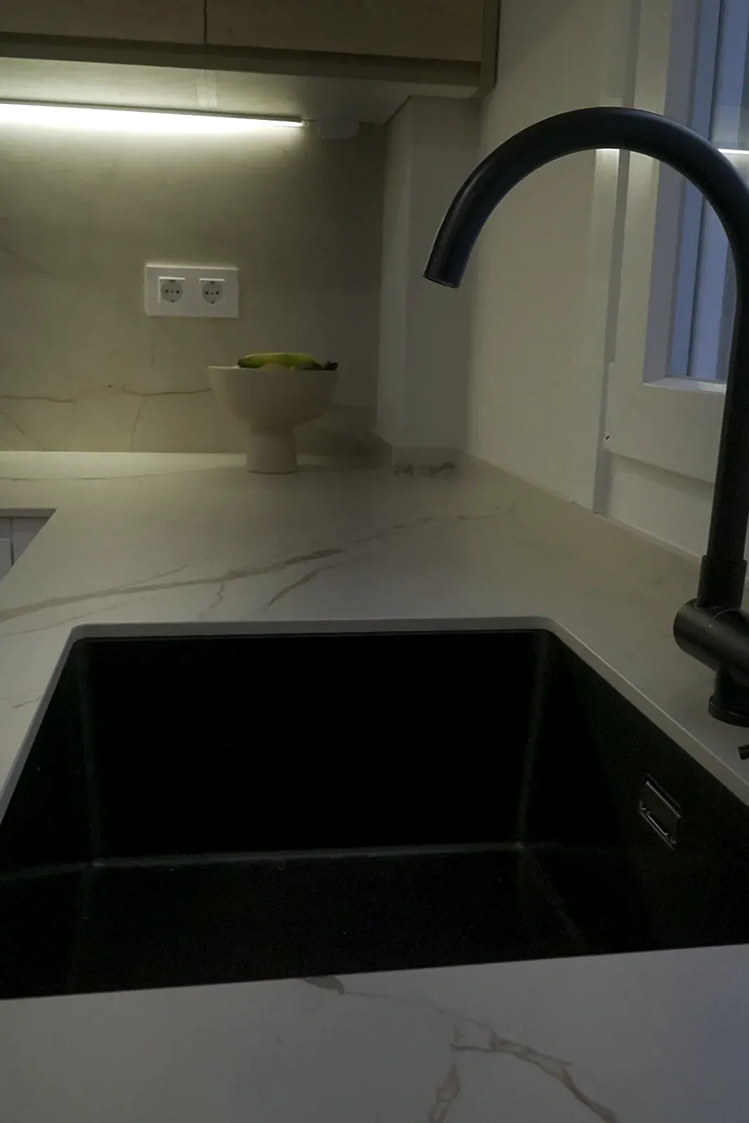 Fregadero negro bajo encimera y grifo negro sobre encimera de mármol en cocina reformada en A Coruña