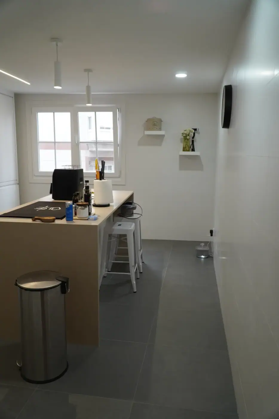 Cocina reformada con isla y ventana a la calle, iluminación lineal en el techo