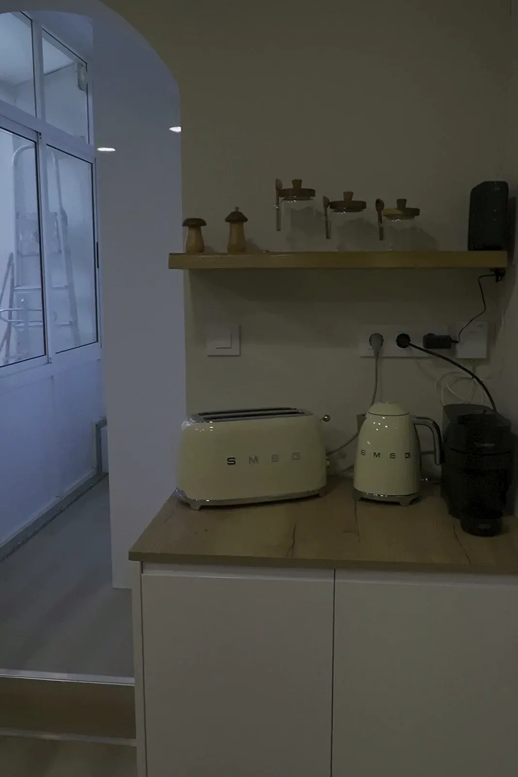 Zona office de cocina reformada con estante de madera y arco a galería acristalada en A Coruña