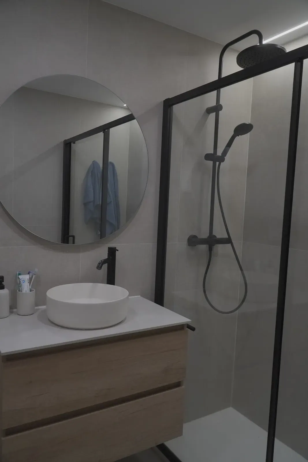Ducha con mampara de perfil negro en baño reformado