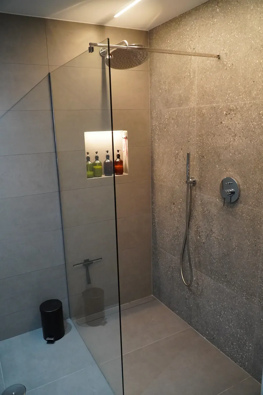 Ducha de obra a ras de suelo con mampara de cristal y hornacina
