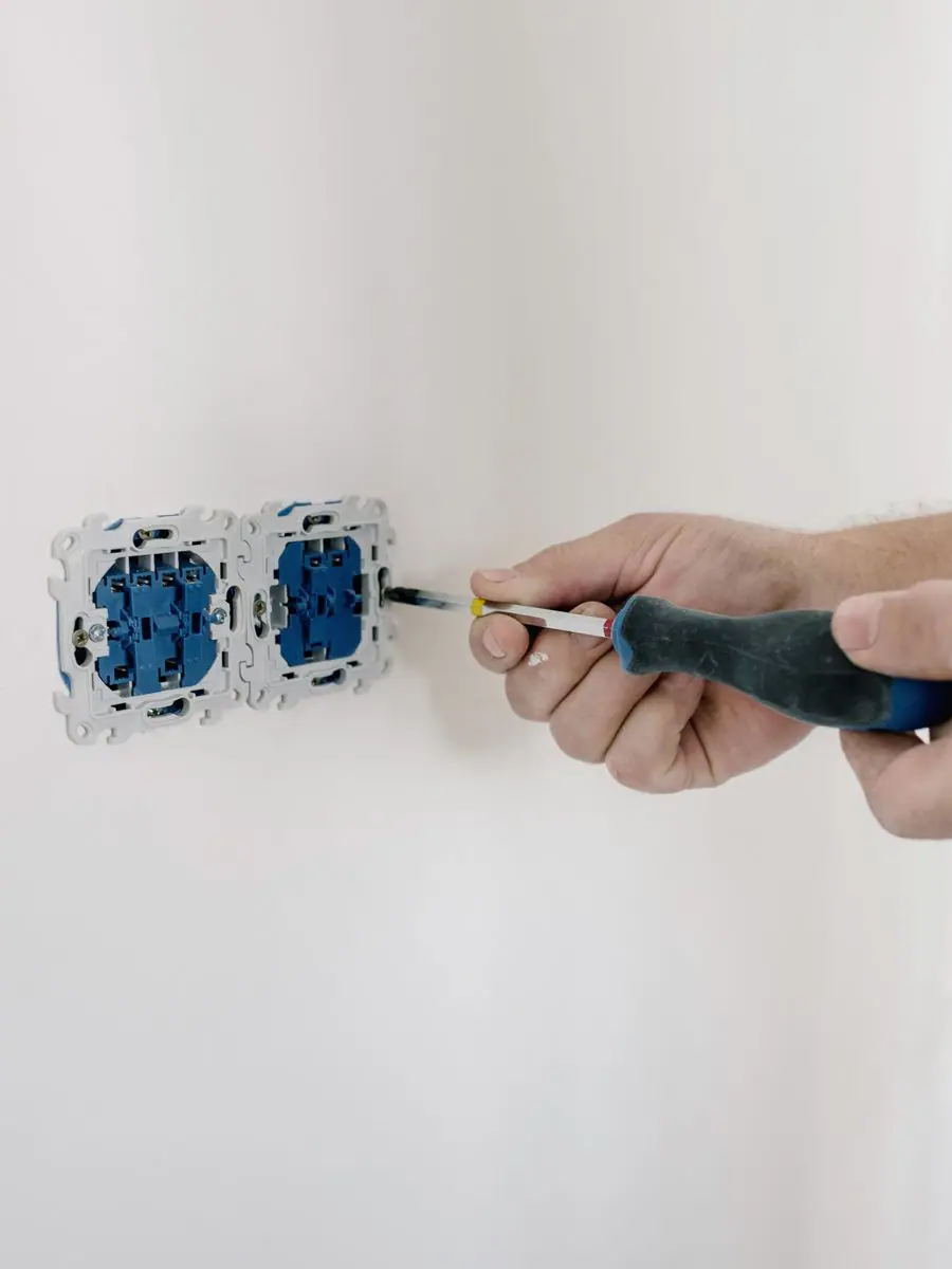 Manos conectando el cable a un mecanismo de enchufe doble antes de embutirlo en la pared